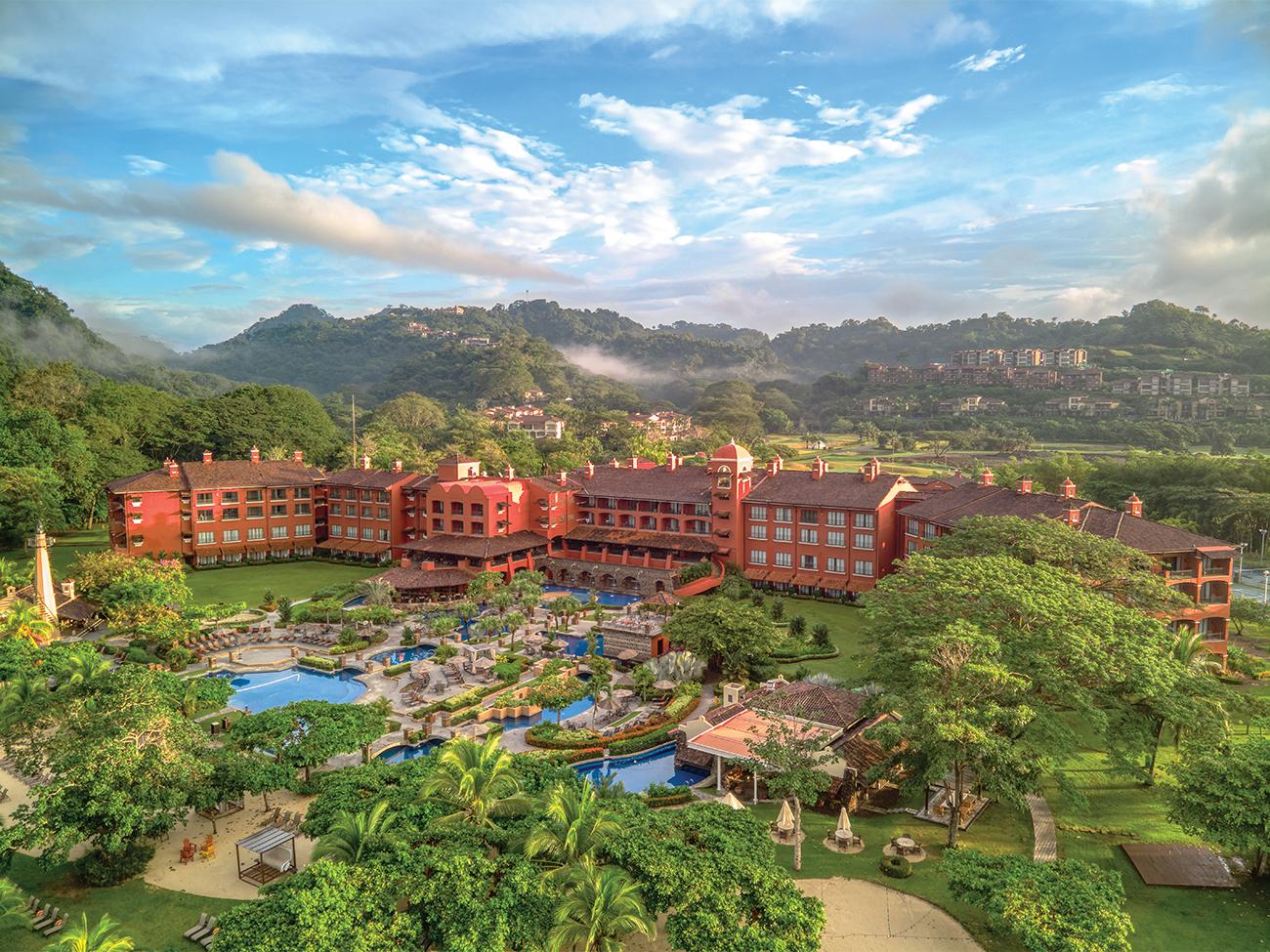 Aerial of exterior and pool at Marriott Vacation Club at Los Suenos resort timeshare with mist-shrouded mountains in distance